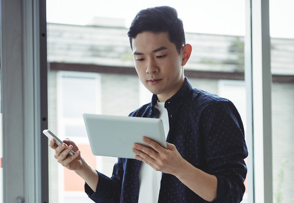Business executive using a mobile phone and digital tablet at their desk